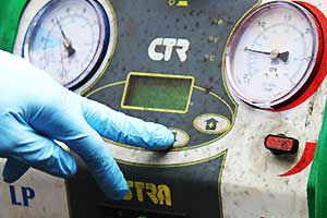 close up of air conditioning regassing equipment being operated by an air con expert sorting light blue gloves