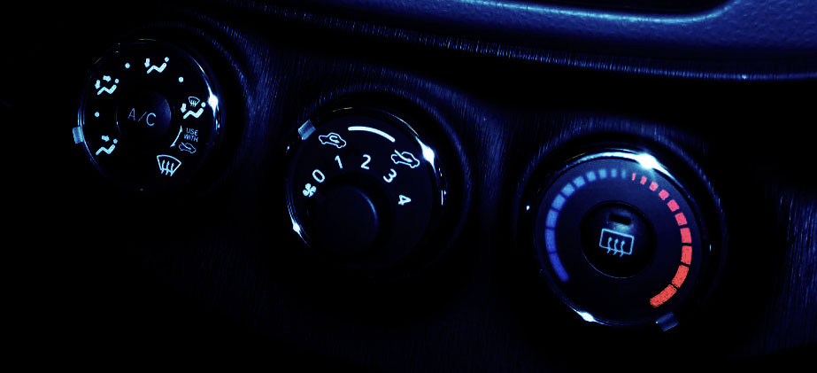 a vehicle black dashboard complete with air conditioning control dials close up