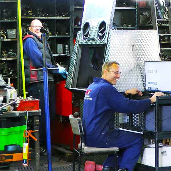 distance view of m and t transmissions garage premises with a gearbox specialit reconditioning a ford gearbox and a mechanic checking on a computer for technical data