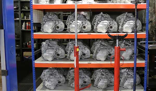 distance front view of heavy rack shelving in blue and orange displaying our many popular reconditioned gearboxes stock with reconditioning all by m and t transmissions