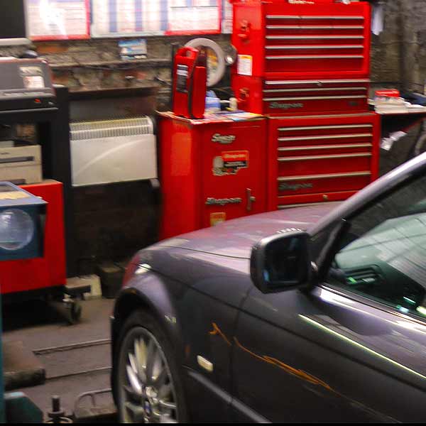 front view from the side of a graphite coloured bmw 325ci sport in the mot test bay receiving its annual mot test